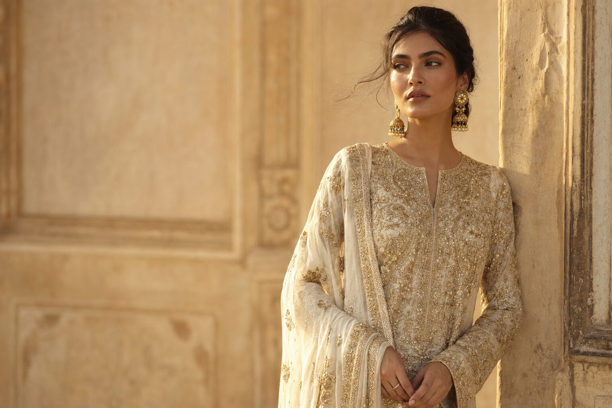 Woman wearing an ivory and gold embroidered occasionwear ensemble